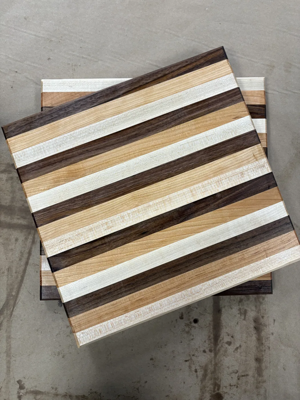 Two finished striped hardwood cutting boards, stacked